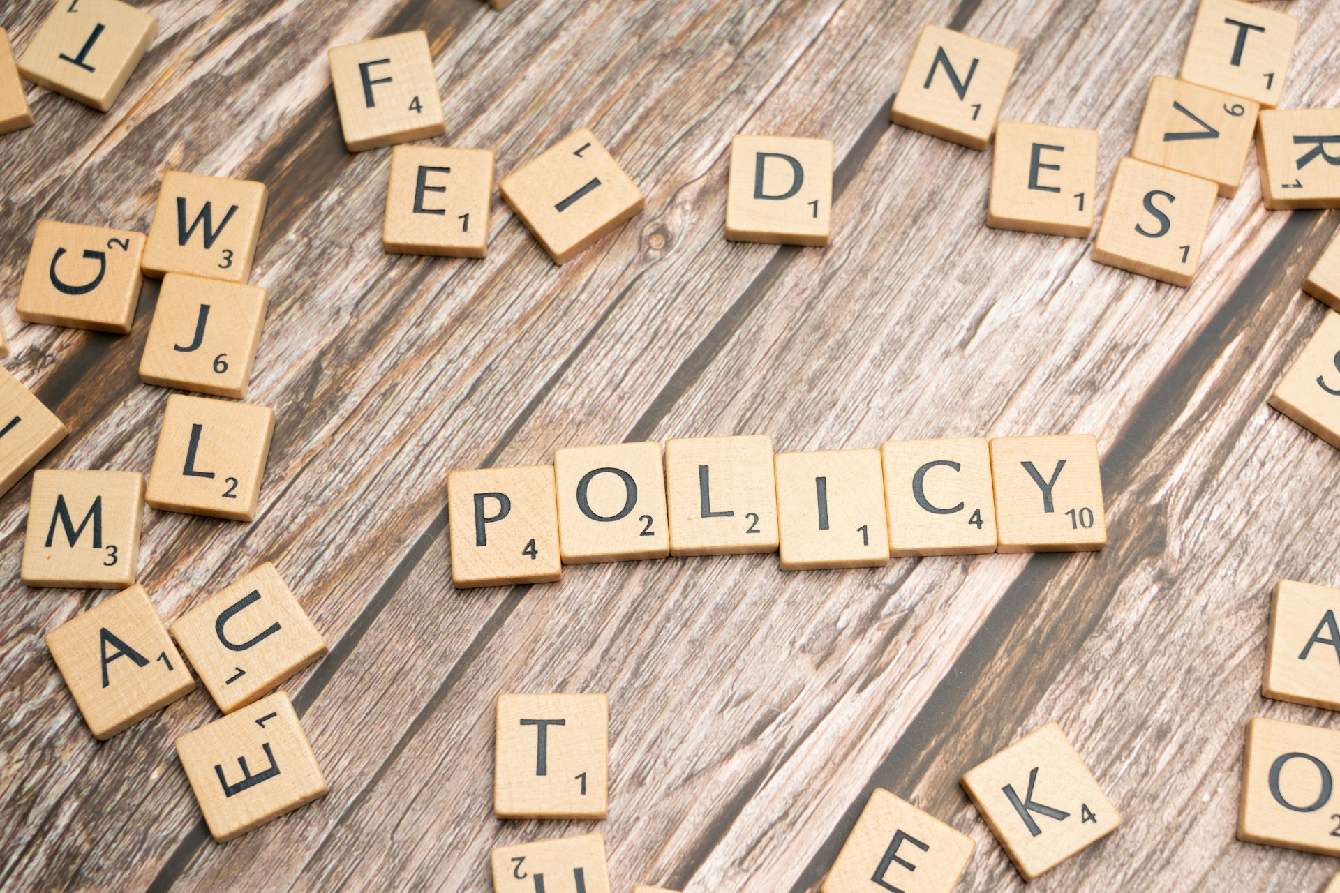 scrabble tiles spelling policy on a wooden table